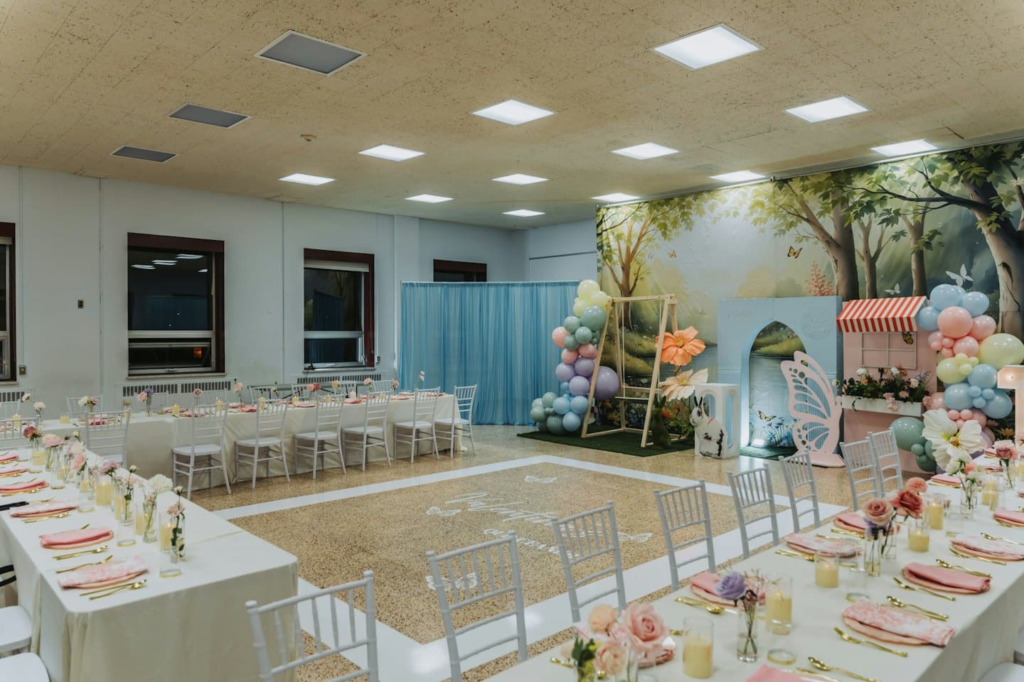 Sala per eventi decorata con tavoli e un murale fiabesco di una foresta.