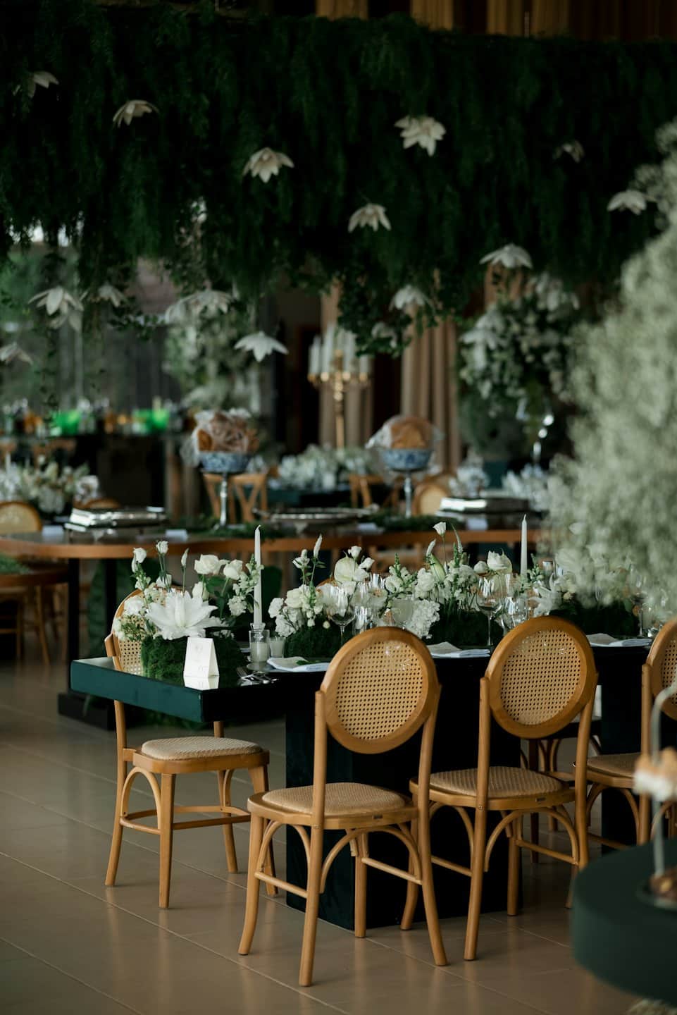 Lunghi tavoli da pranzo decorati con composizioni floreali e candele.