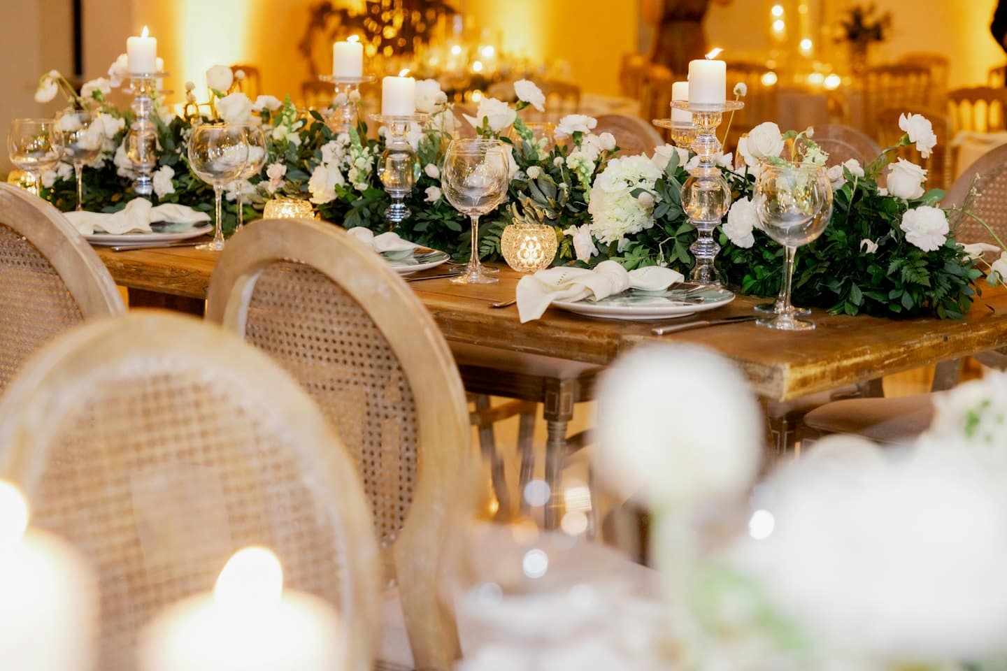 Elegante tavolo da evento con centrotavola floreale e candele accese.