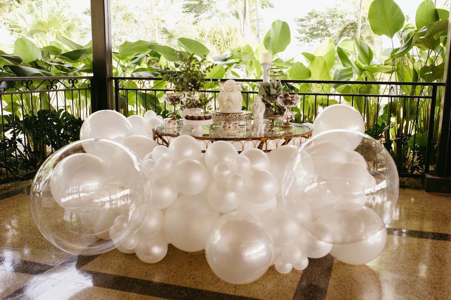 Ghirlanda di palloncini bianchi incornicia un tavolo da dessert con una torta a più piani.